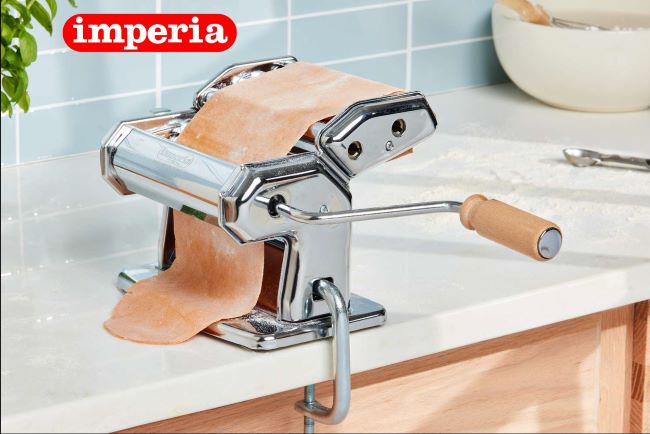 Homemade pasta being rolled using an Italian pasta maker.