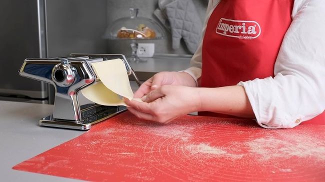 Close-up of Italian pasta maker with dough and pasta sheets.