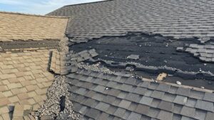 Damaged asphalt shingles on residential roof showing curling edges and missing granules indicating need for replacement