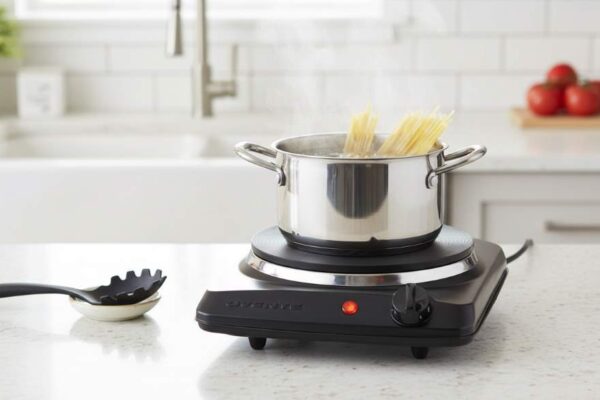 OVENTE 1000W single burner hot plate with cast-iron plate heating a pot of pasta on a kitchen counter