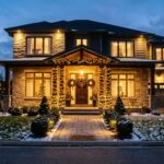 Warm string lights and holiday wreaths illuminate a festive porch.